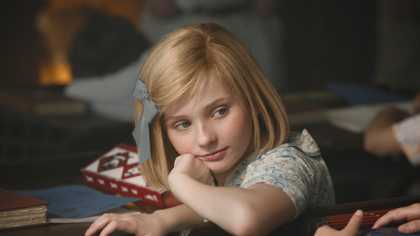 A young schoolgirl listening thoughtfully to one of her friends during class.